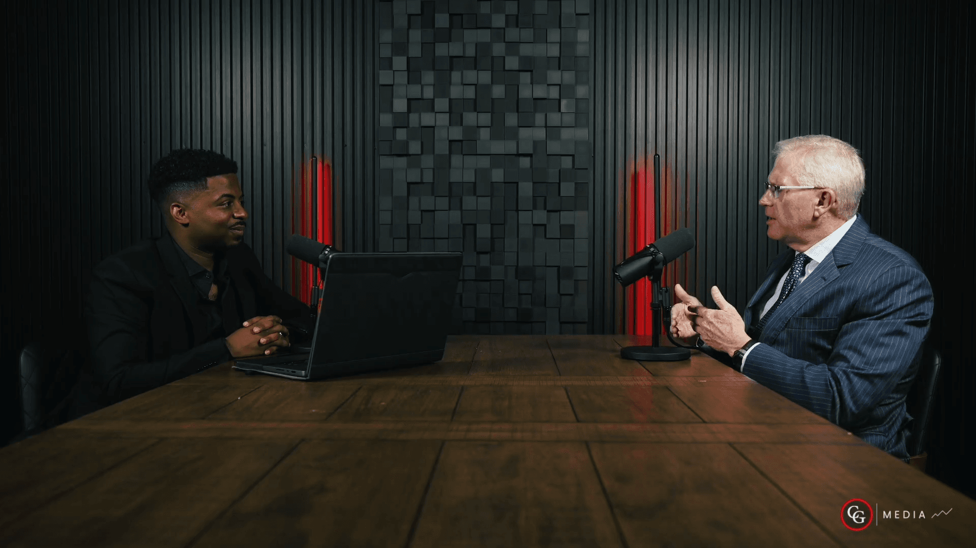 Host Elvis Casely (left) interviewing attorney Joseph Ingram (right) during an episode of 60 Minutes: Inside Trial Minds, seated at a studio table with microphones.