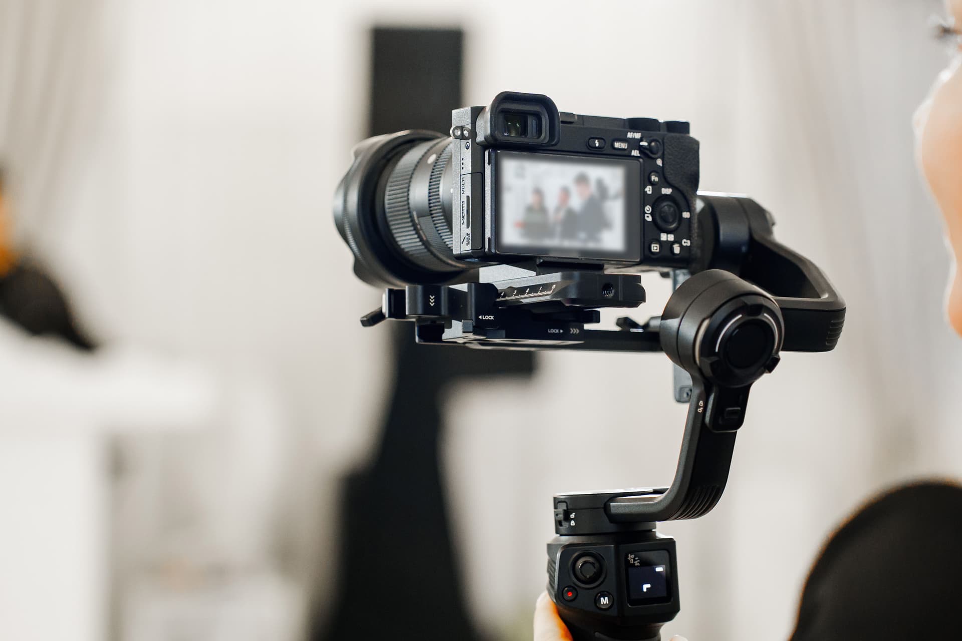 Professional video camera on a stabilizer recording a person during a shoot in a studio setting.